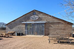 Wood-sided Albert Dance Hall with picnic tables in Albert, Texas