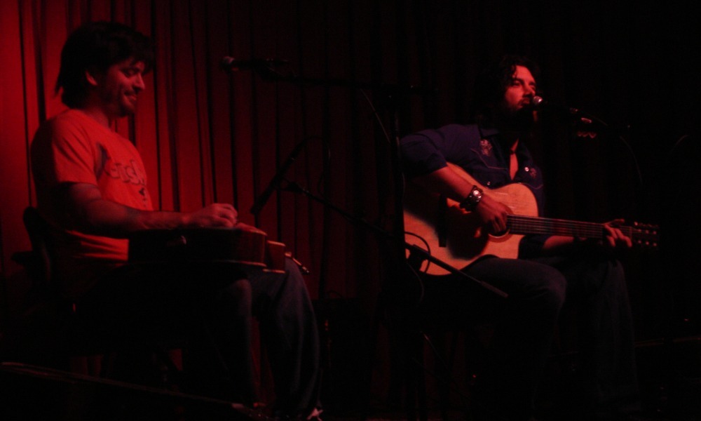 Bob Schneider performing live on stage with guitar