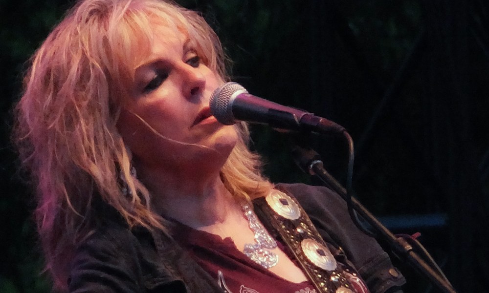 Lucinda Williams singing at a microphone before her Dallas concert
